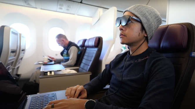 A man using Rokid Max TV glasses on the plane